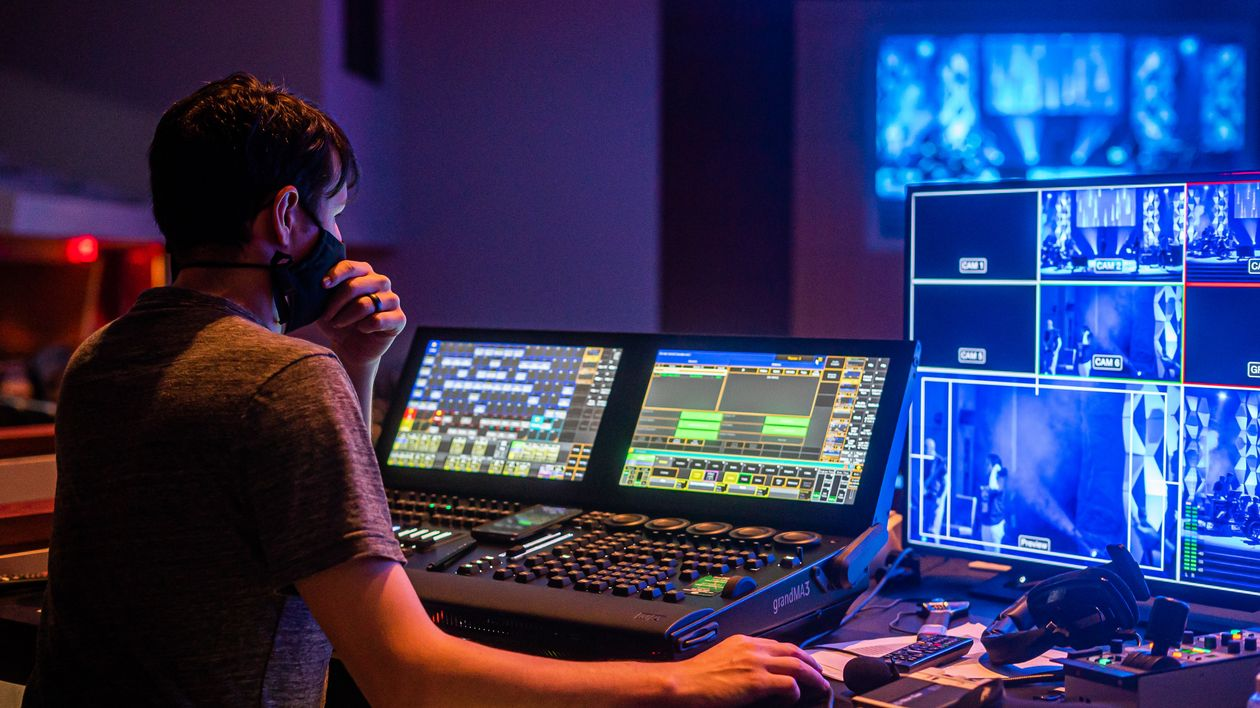 Lighting technician operating a grandMA3 lighting console at a live event