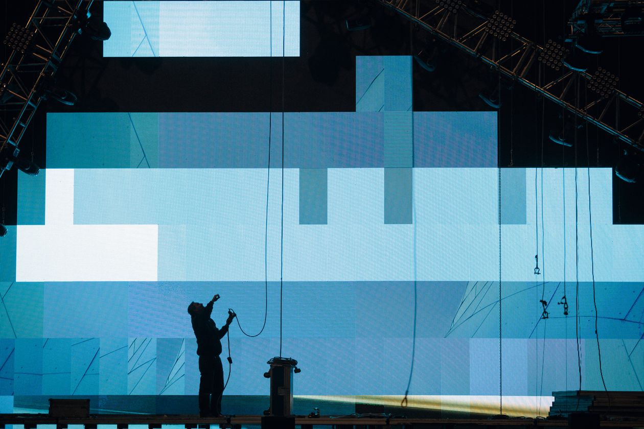 Production technician working on a large LED video wall on stage