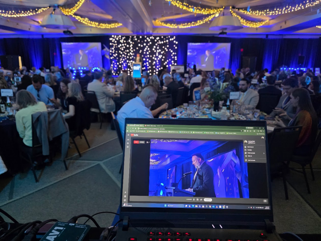 Gala ballroom with laptop showing YouTube livestream of the event