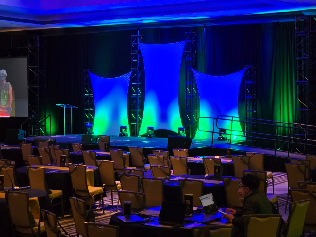 Corporate gala stage with blue and green uplighting and white sails