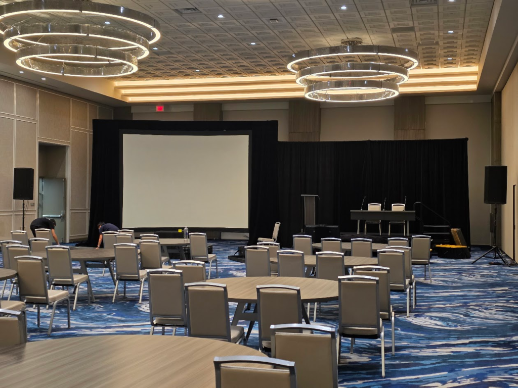 Hotel ballroom with large projection screen and black drape