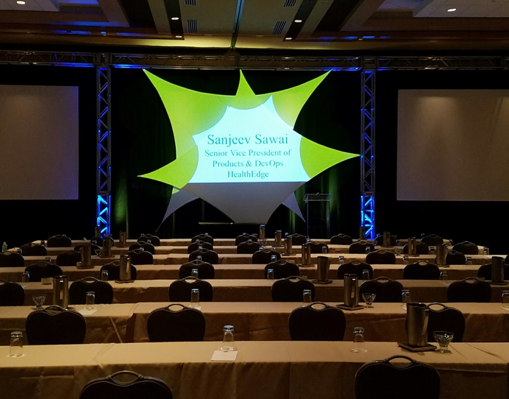 Keynote stage with green-lit sail backdrop at HealthEdge event