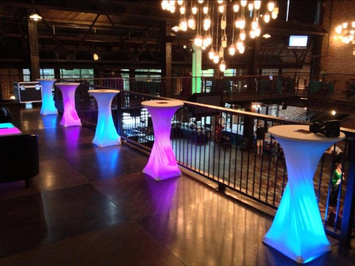 Glowing LED cocktail tables lit in blue and purple on a venue mezzanine during cocktail hour